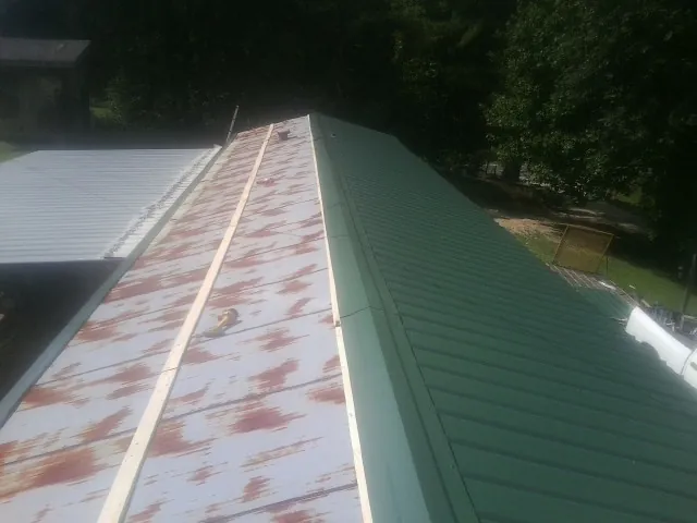 Old rusted panels beside newly installed green metal roofing — Wind Damage Roof Repair by Roofing Brothers in La Crescent