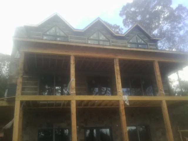 Dormers and porch framing on a large log home under construction — Roof Coating work by our crew in La Crescent