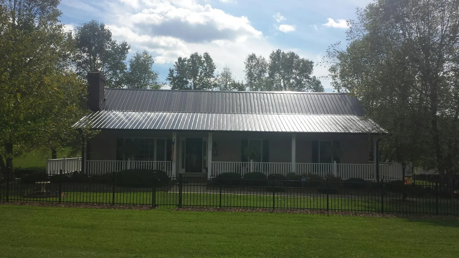 Gray metal roof on a brick ranch with a full width front porch — Gutter Guard Installation work by our crew in La Crescent
