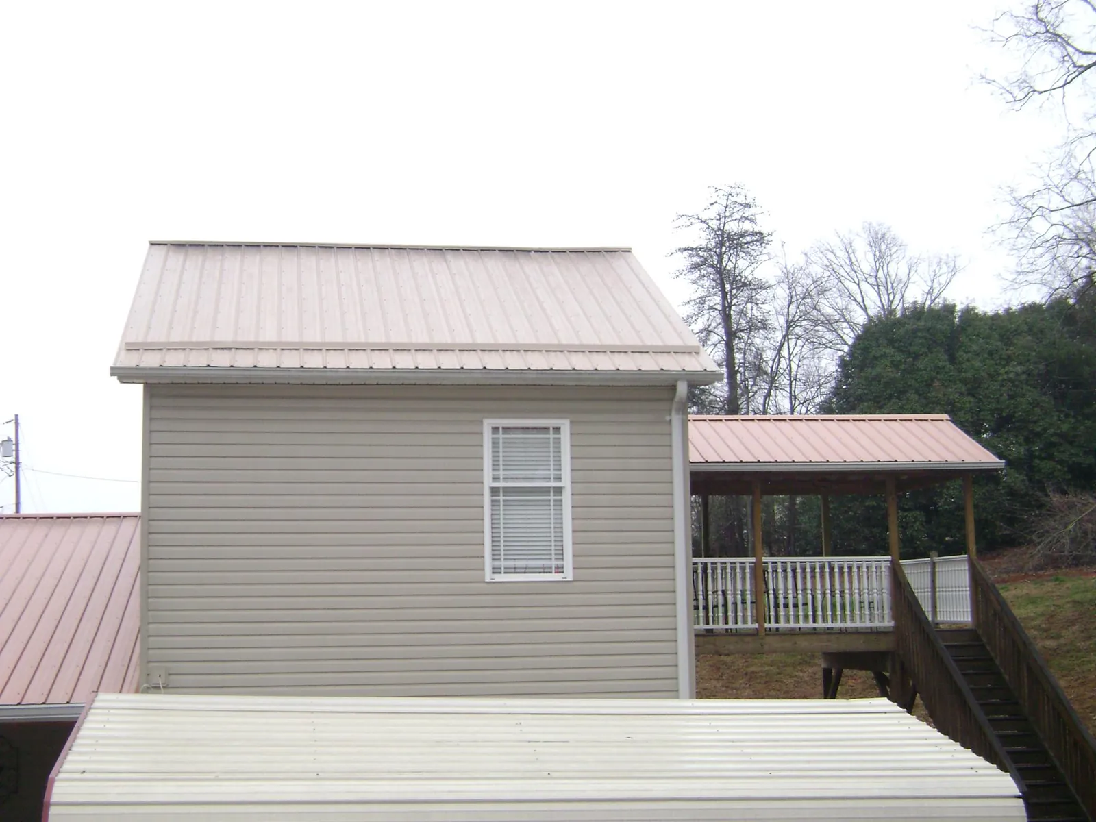 Tan metal roofs on a two story addition and attached porch, from a Roof Replacement job in La Crescent