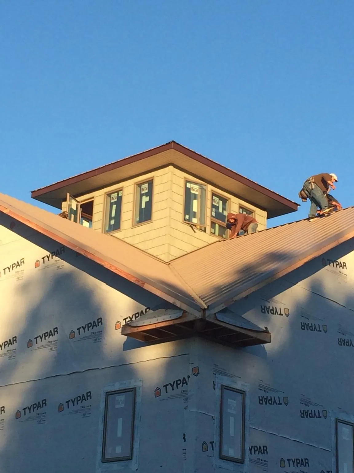 Roofers working around a rooftop cupola on a new metal roof at sunset — Roof Waterproofing in La Crescent by Roofing Brothers